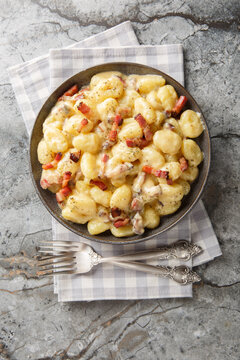 carbonara gnocchi, bathed in a velvety sauce crafted from creamy egg yolks and decadent closeup on the plate on the table. Vertical top view from above