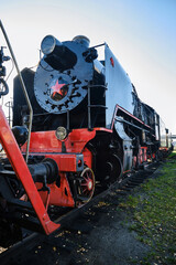 Old steam locomotive in the countryside.  Steam locomotives with red star on the railroad tracks. © VLAD ANTONOV