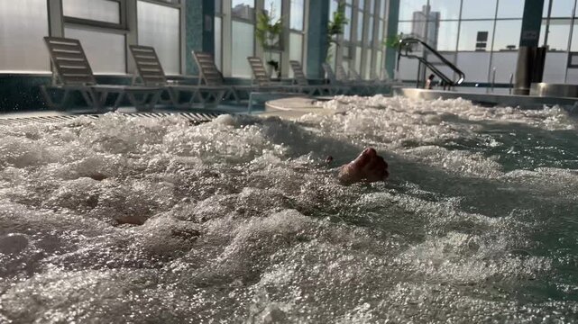 Adults recline in bubbling spa water with bare feet visible, leisure time, personal wellness, indoor relaxation.