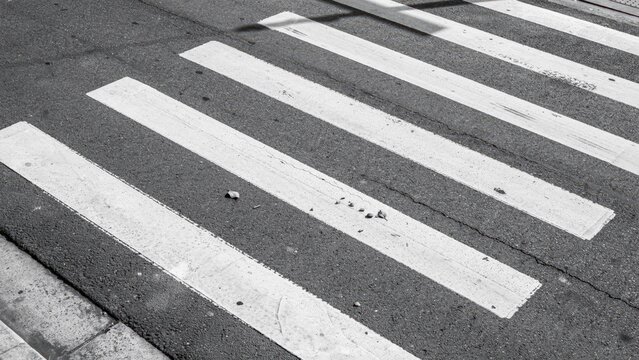 A black and white close-up of a crosswalk on a city street