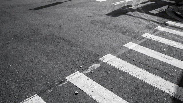 A black and white photo of a crosswalk on a city street with asphalt