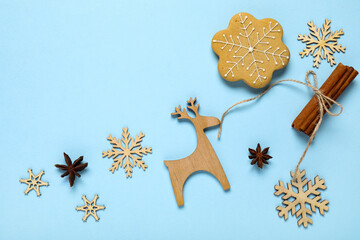Christmas holiday celebration and winter season concept, gingerbread snowflake cookie with wooden reindeer ornament and cinnamon sticks on blue background © Pixel-Shot