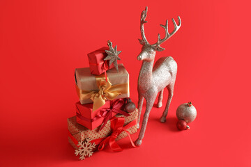 Christmas gift giving and holiday celebration, stack of wrapped presents with silver reindeer ornament and festive decorations on a solid red background © Pixel-Shot