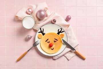 Christmas breakfast and holiday food fun, reindeer pancake with raspberry nose and chocolate antlers on a plate with milk and festive ornaments © Pixel-Shot