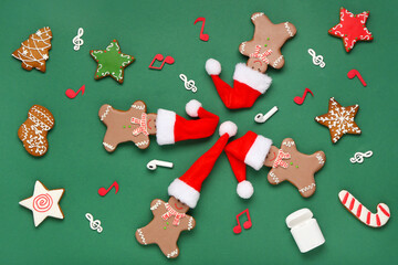 Fototapeta premium Composition with Christmas cookies in Santa hats, earphones and note signs on green background