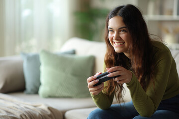 Happy young woman playing video game using controller © Antonioguillem
