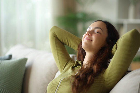 Satisfied young woman is relaxing and resting at home