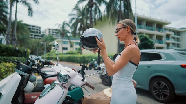 Tourist woman rent motorbike in Asian country, lady putting helmet before ride. Rental service for travelers in Vietnam, Thailand and Asian countries, safety for life, compliance with traffic rules