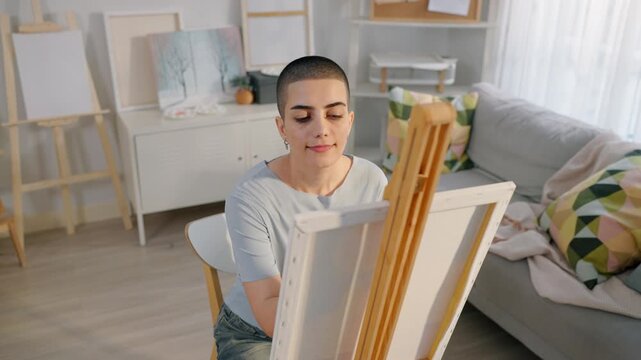 Caucasian female artist painting artwork on canvas frame at home studio. 