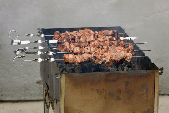Delicious marinated pork skewers sizzling and smoking over hot charcoal in an outdoor metal grill