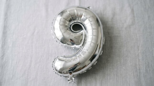 Shiny Metallic Silver Balloon In The Shape Of Number Nine Isolated On A Light Grey Textured Fabric Background For Birthday Or Anniversary Celebration