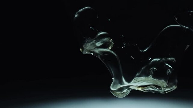 A Captivating Dance of Fluidity: The Iridescent Movement of Dark Liquid Shapes Captured in Stunning Detail Against a Minimalist Background