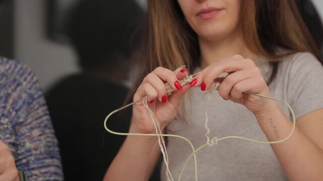 Young woman knitting with yarn and needles at home