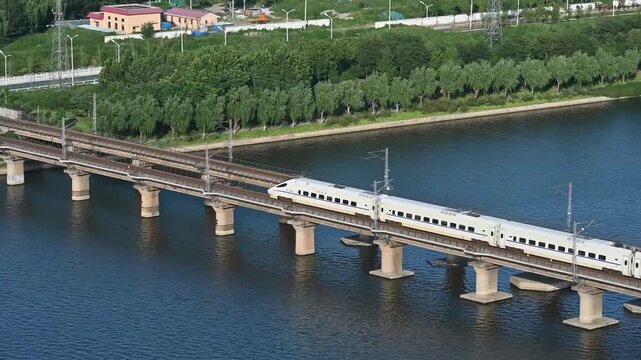 High-speed CRH train crossing a multi-track railway bridge over a wide river in daylight