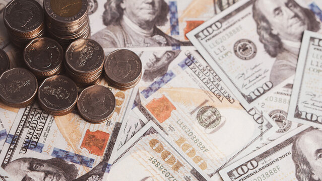 Dollar banknotes and baht coins show mixed currency and financial value. Close-up money concept for investment, savings, foreign exchange, global finance, banking, trade, wealth and economic content.