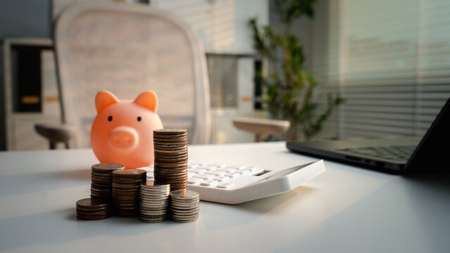 Piggy bank and coin stacks represent saving and financial planning. Calculator and laptop create a personal finance scene for budgeting, investment, accounting, retirement and wealth growth.