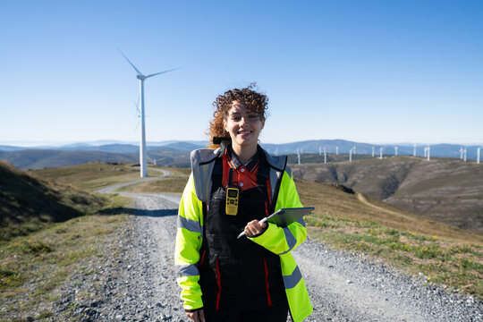White woman engineer inspecting wind turbines at mountain wind farm