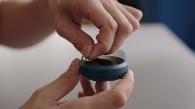 Unboxing new portable wi fi router, hands peeling off protective film from surface, concept of wireless internet access and mobile hotspot connectivity, close-up, slow motion.