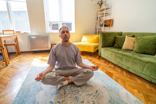 Man meditating at home with breathing and mindfulness after stress, restoring calm, emotional wellbeing and healthy solitude during quiet self care reset.