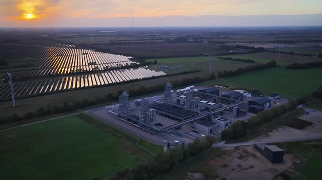 Aerial footage of E-methanol power-to-x plant in Denmark. State-of-the-art Power-to-X facility by green fields and vast solar park showcasing integration of renewable energy and green fuel production.