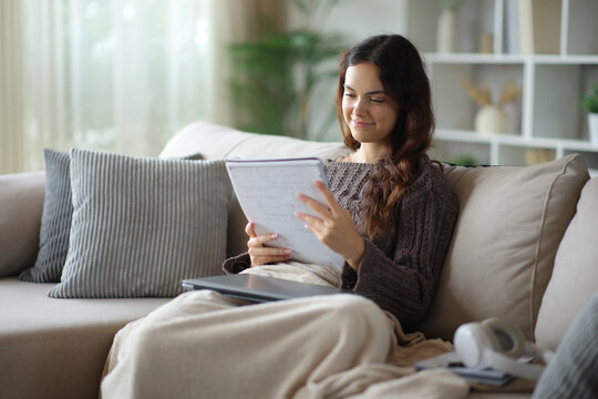 Satisfied student memorizing paper notes studying at home in winter