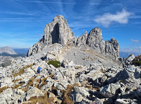 Massive rock face with scenic view of mountain peak TAC Spitze, Hochschwab Alps, Styria, Austria. Steep rocky cliffs with man.