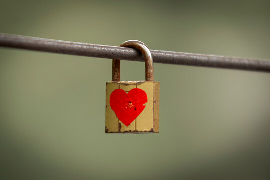 Love padlock with red heart hanging on metal railing