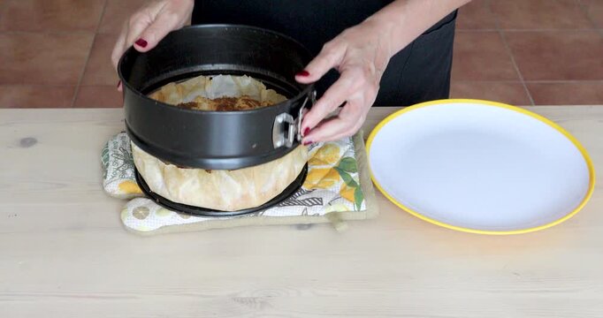 Baked Puff Pastry Apple Pie Removed from Springform Pan onto Plate. A freshly baked apple pie with puff pastry crust is carefully released from a round springform pan and transferred onto a serving pl