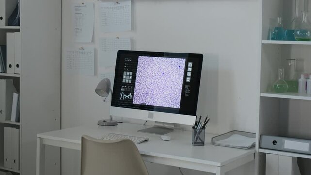 Computer monitor displaying microscopic cellular analysis in modern laboratory workstation. Footage suitable for pharmaceutical research and biotechnology marketing campaigns