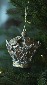 Vertical video. Hands hanging Christmas ornaments on Christmas tree. 