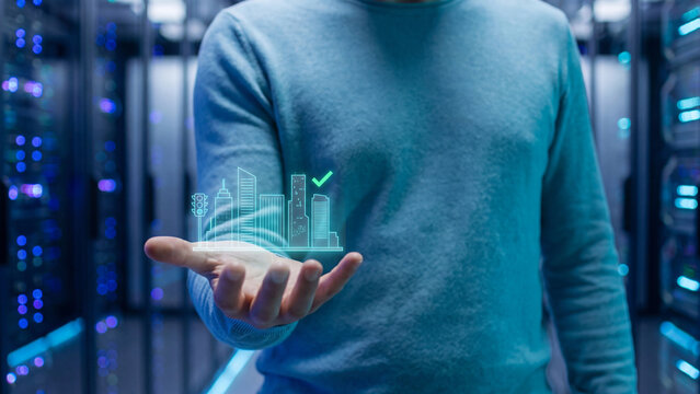 Smart city and urban infrastructure concept, hand holding building skyline with traffic light in server room for digital technology network, construction planning and sustainable future