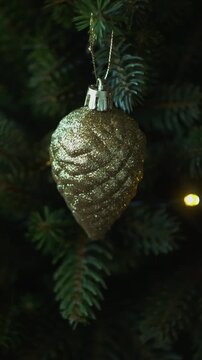 Vertical video. Woman decorating Christmas tree with Christmas ornaments.