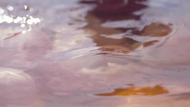 Water ripples reflect sunset sky in a sauna pool