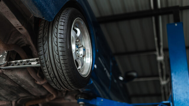 Car Tire And Wheel On Hydraulic Lift In Garage Service