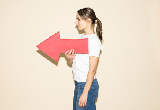 Woman holding red paper arrow pointing forward indicating direction