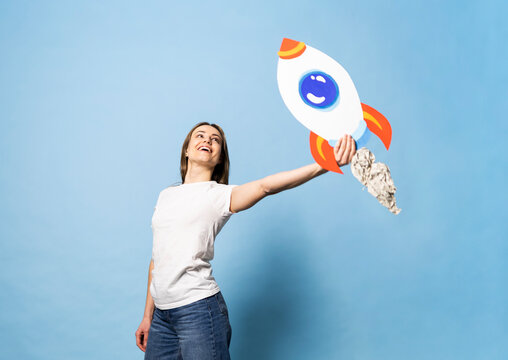 Smiling entrepreneur holding handmade paper rocket for success