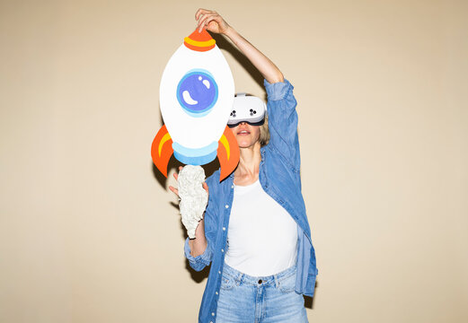 Woman wearing VR glasses holding a handmade paper rocket