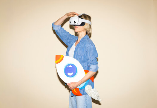 Woman in virtual reality display holding paper rocket indoors