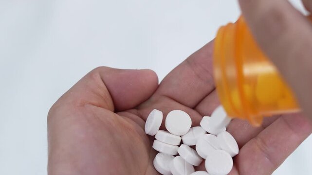 close up woman hand holding a medicine, with pours the pills out of the yellow orange medicine bottle. Stop drug use Taking Medication Caring for the health care medical concept.
