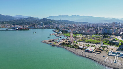 Obraz premium Aerial view of Batumi beach and embankment with green mountains background along Black Sea coast in Adjara Georgia during clear sunny summer day