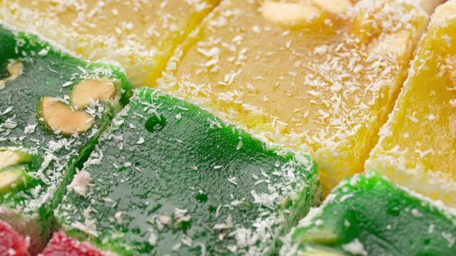 Assorted colorful Turkish delight sweets with nuts and coconut flakes rotating slowly close up. Rahat Lokum	

