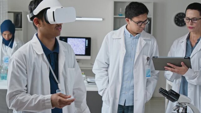 Multiethnic scientists conducting research using virtual reality headset and digital tablet in laboratory. Perfect for advertising biotech innovation and immersive medical training