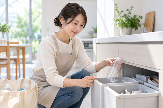 自宅キッチンでペットボトルを分別する女性