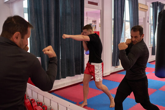 Kickboxers shadowboxing at gym mirror