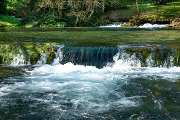 Scenic view of small water cascades and clear emerald stream flowing through lush green forest at Vrelo Bosne nature park, Bosnia and Herzegovina © Aleksandar
