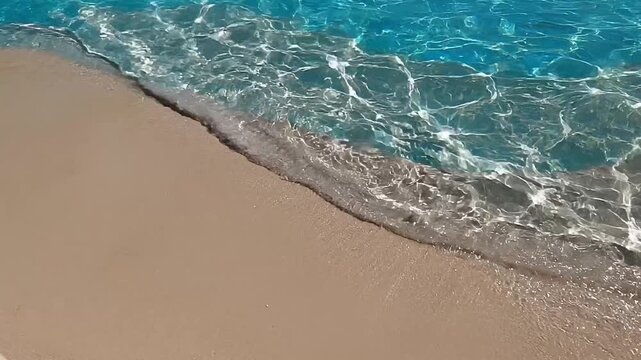 Gentle crystal clear beach water waves with sunlight caustics on sand 4k