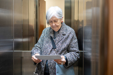 Senior woman reading mail in apartment elevator © GREGORIO