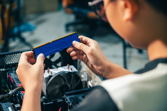 Young boy concentrating while repairing and assembling hardware inside an open desktop computer case at home, learning technology and problem solving skills