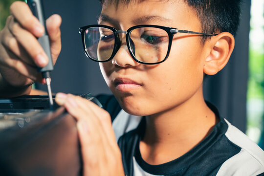Young boy concentrating while repairing and assembling hardware inside an open desktop computer case at home, learning technology and problem solving skills