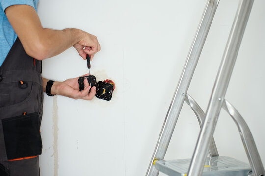 Man installing electrical outlets in wall with screwdriver